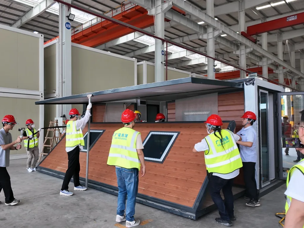 Workers installing a modular expandable container house on site